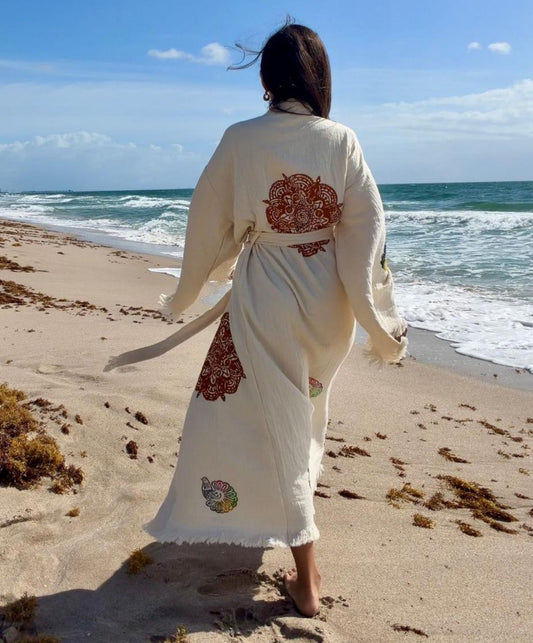 Woman wearing a handmade organic cotton covered up swimwear robe on the beach, styled as an elegant lightweight resort cover up.