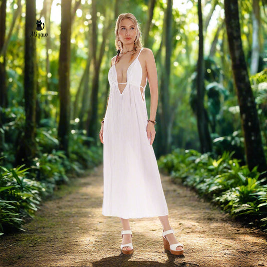 A glorious woman wears a white maxi dress in heels in a jungle