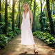 A glorious woman wears a white maxi dress in heels in a jungle