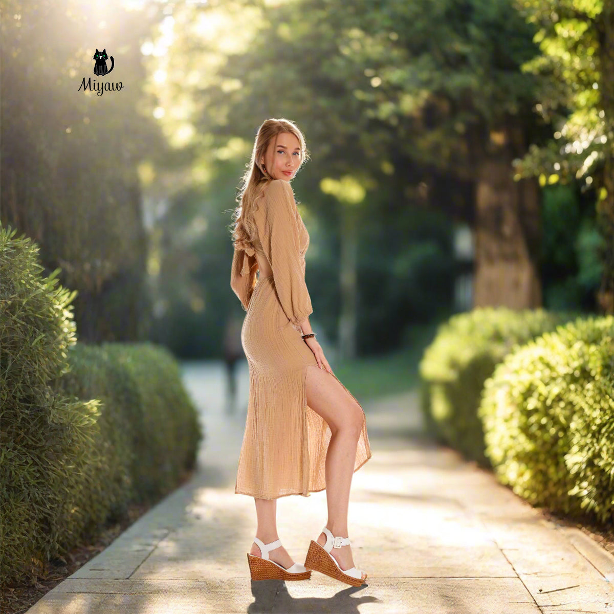 A woman wears a cut-out maxi dress in heels.