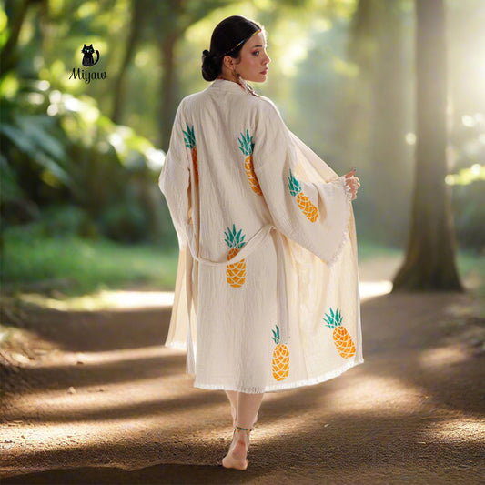 A woman gracefully dons a flowing Boho Pineapple Kimono Robe, her bare feet softly brushing against the ground.A woman is wearing a kimono robe and is barefoot.