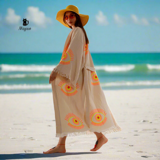 A woman wearing an evil eye kimono Robe is walking on the beach