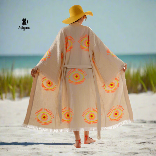 A woman wearing an evil eye kimono Robe is walking on the beach