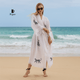 A woman wearing a white robe with black animal prints on a beach, with 'Miyawfashion' branding.