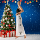 Woman in a black top and white pants with reindeer designs standing next to a decorated Christmas tree and presents.