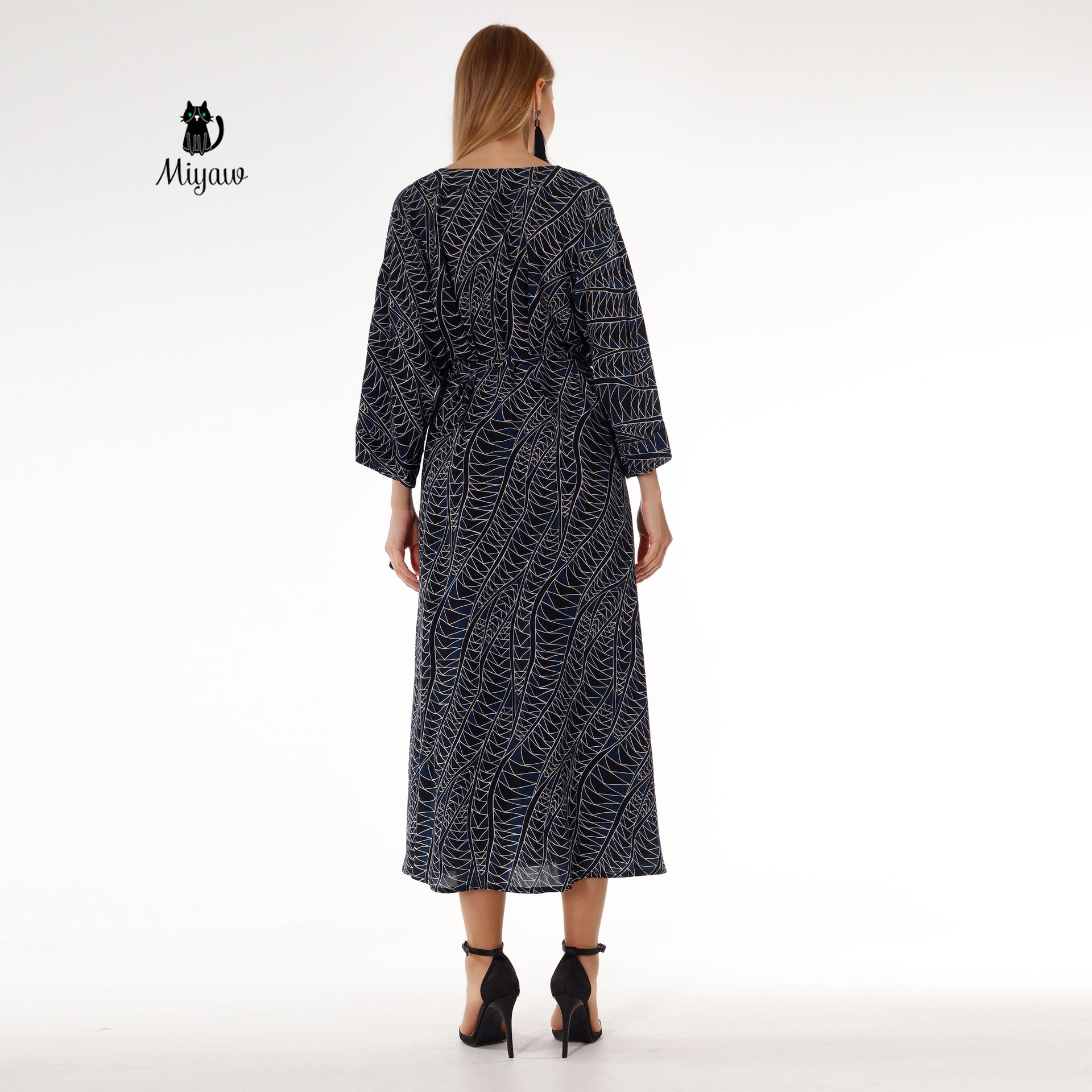 Stylish black long sleeve maxi dress worn by woman, chic resort wear look
