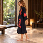 Side view of a woman wearing a black dragon-print kimono robe, showing the wide sleeve, belted waist and fringed hem.