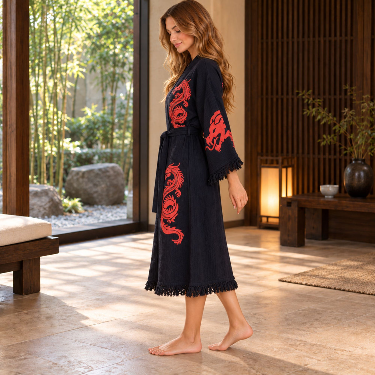 Side view of a woman wearing a black dragon-print kimono robe, showing the wide sleeve, belted waist and fringed hem.