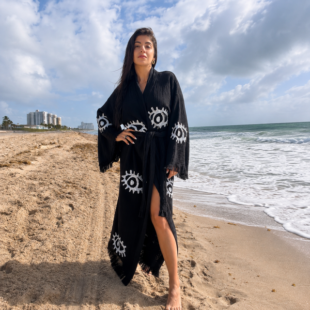 Handcrafted black women's 100% cotton kimono robe with white Evil Eye motifs worn as a lightweight beach cover-up and resort robe by MIYAW Fashion.