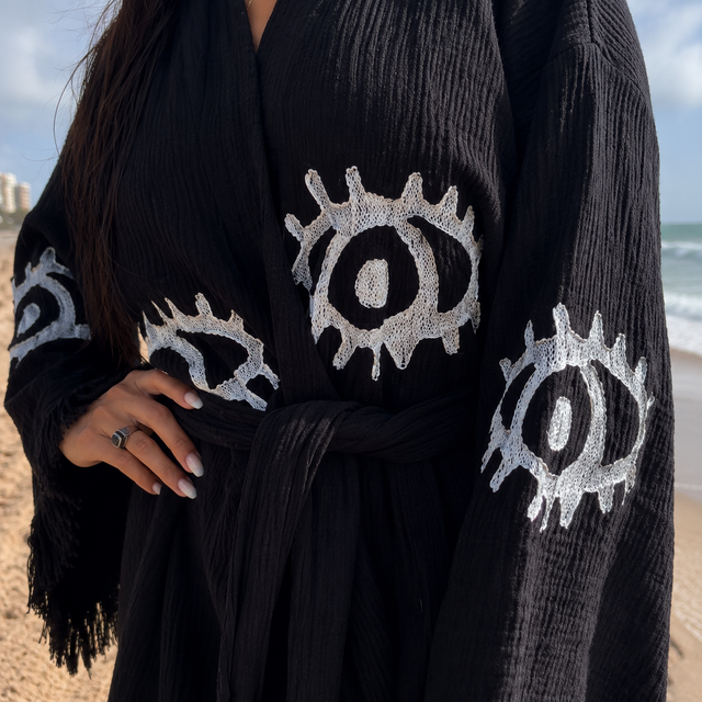 Close-up of the handcrafted white Evil Eye embroidery on a black 100% cotton kimono robe.