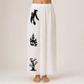 White Halloween pajama pants with black witch, haunted house, and spooky tree print.