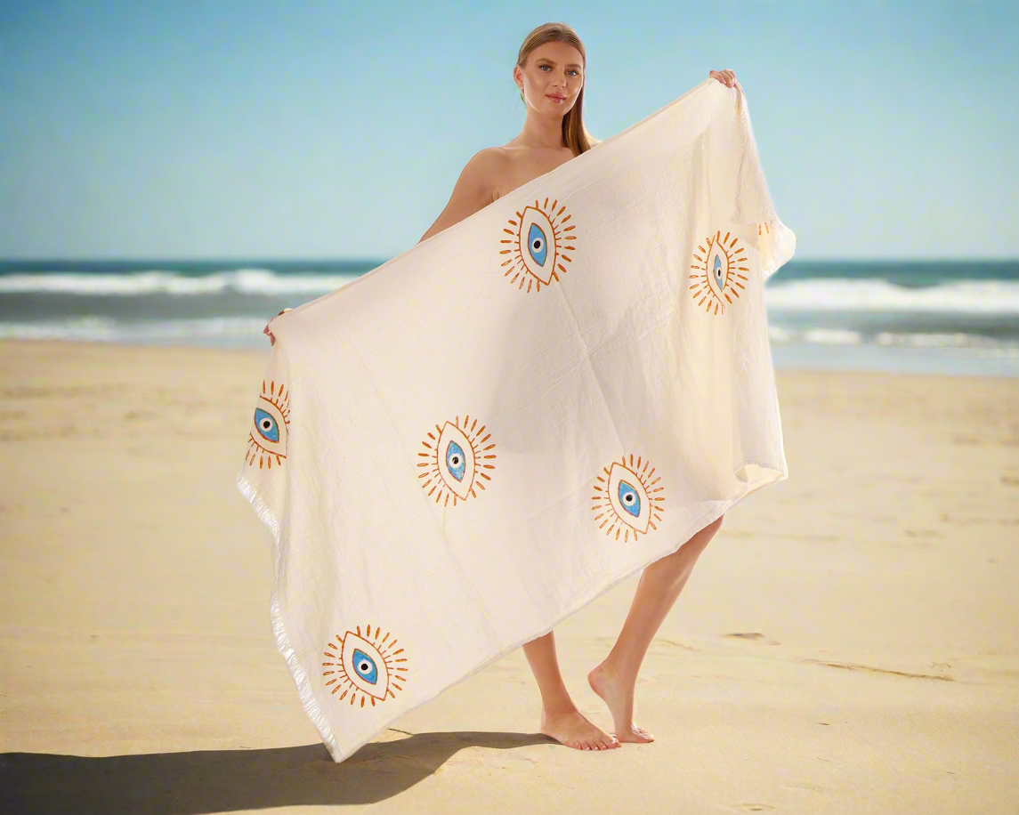 A woman is wrapped in a boho beach towel while enjoying the beach.